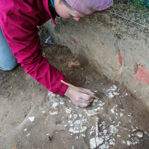 Caitlin Delmas excavates plaster at the north Church Tower site.
