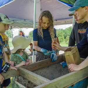 Staff Archaeologist Natalie Reid and campers share some of their finds with visitors.