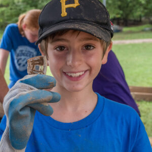A kids camp attendee holds a piece of a glass vessel he found while screening.