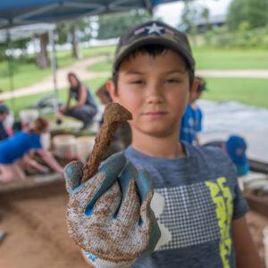 A camper holds an iron spike he found at the cellar excavations.