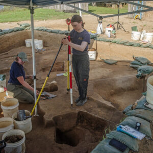 Archaeological Field Technician Eleanor Robb excavates and Staff Archaeologist Natalie Reid prepares for survey work at the 1607 Burial Ground.