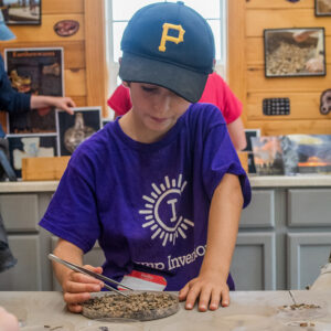 A camper in the Ed Shed searches for artifacts in objects excavated from the fort's first well.