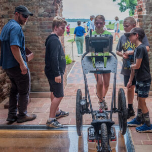 Director of Archaeology Sean Romo instructs campers in use of one of the ground-penetrating radar (GPR) machines. The kids are surveying inside the 1680s Church Tower where the remains of the 1617 church's west foundations lie under a glass floor.