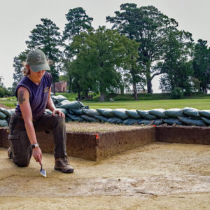 Archaeological Field Technician Ren Willis points to the burial that will be excavated south of the Archaearium.