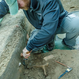 Senior Staff Archaeologist Sean Romo excavates an iron object at the north Church Tower excavations.