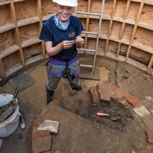 Staff Archaeologist Natalie Reid holds a sherd of Virginia Indian pottery that she found while excavating the Governor's Well.