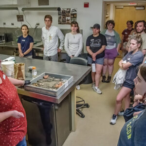 Collections Assistant Lauren Stephens talks to the field school students about the process artifacts undergo after coming in from the field.