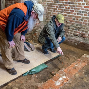 Archaeologists examine brick foundations in a brick church tower