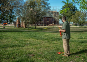 two people laying out a transect line in a grassy area using a long tape measure