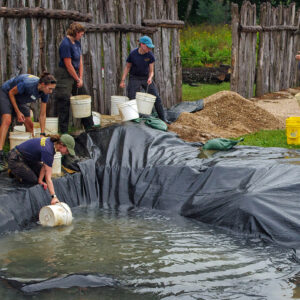 The archaeological team forms a bucket brigade to remove water from the 1607 burial ground following a rainstorm.