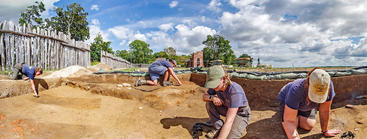 The Jamestown Rediscovery archaeologists excavate a section of the 1607 burial ground. The two dark horizontally-aligned rectangles at the left of the photo are burials.