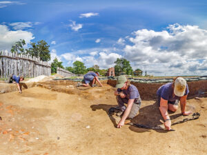 The Jamestown Rediscovery archaeologists excavate a section of the 1607 burial ground. The two dark horizontally-aligned rectangles at the left of the photo are burials.