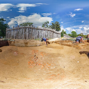 The Jamestown Rediscovery team prepares the area of the 1607 burial ground where this year's burial excavations will take place. The three dark rectangles are the top of the grave shafts. The brick scatter at center may be a robbed hearth from a later building. The brick and cobblestone feature at left is a chimney base for a fort-period building that paralleled the west palisade wall and was approximately 92 feet long.