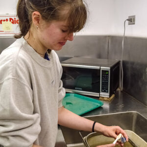 Field school student Sofia Zate cleans a sherd of pottery in the lab.