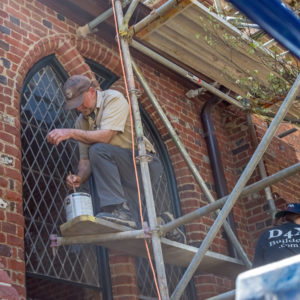 Craftsman on scaffold paints Memorial Church windows