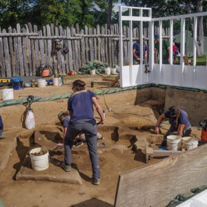 While some of the crew conduct excavations, other archaeologists combine building sections to construct the burial structure at the 1607 Burial Ground.