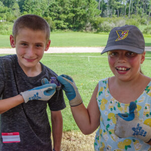 Two campers hold mending ceramic sherds they found while screening at the cellar excavations.