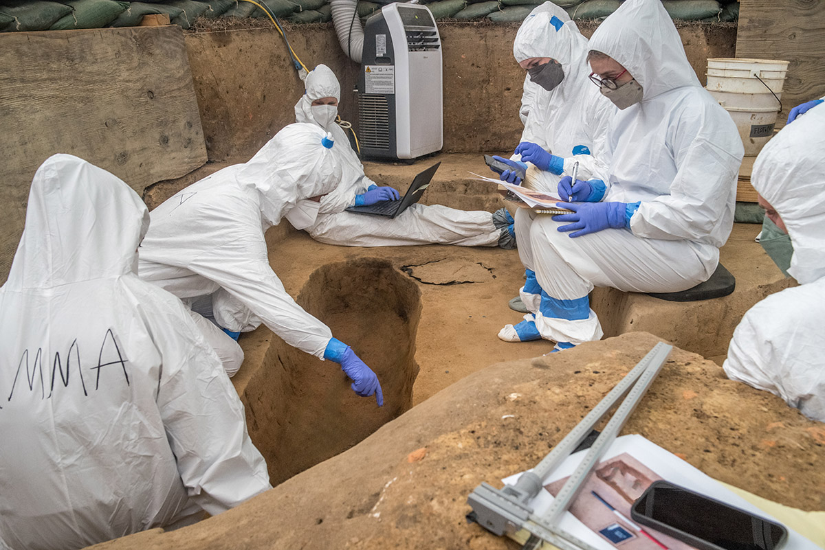 The archaeological team examine one of the burials and take records of their findings. Human remains digitally removed from photo.