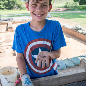 A camper holds lead sprue he found while screening. This sprue is the waste portion of shot produced via a gang mold.