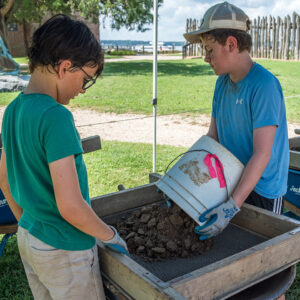 Emptying excavated soil into a screen prior to looking for artifacts