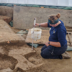 Archaeological Field Technician Hannah Barch double checks her elevation inside of the 1607 Burial Ground structure.