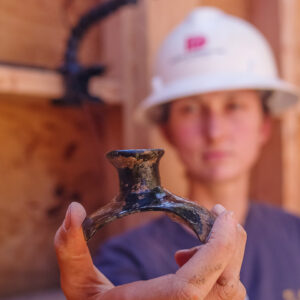 Site Supervisor Anna Shackelford holds a fragment of a case bottle found in the Governor's Well.