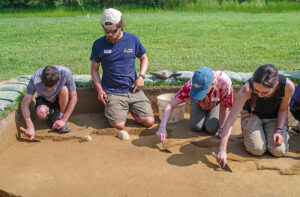 Field school students and staff trowel a test unit at the North Field site.