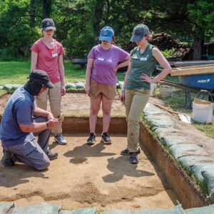 Senior Staff Archaeologist Sean Romo teaches proper troweling techniques to some of the Field School students.
