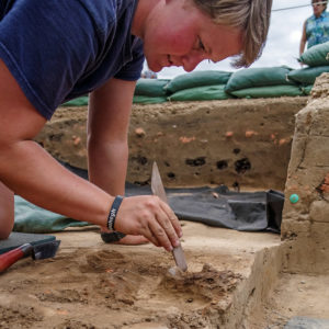 Staff Archaeologist Caitlin Delmas excavates brigandine armor found in the pit of the north Church Tower excavations.