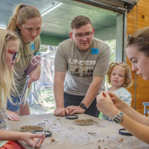 Public Archaeology Intern Seneca Humphries shares a tiny find with visitors in the Ed Shed.