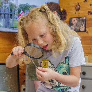 A visitor examines a tiny artifact she found in the Ed Shed.