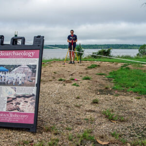 Senior Staff Archaeologist Anna Shackelford uses surveying equipment at the 1607 burial ground to lay out the borders of the upcoming excavations there.