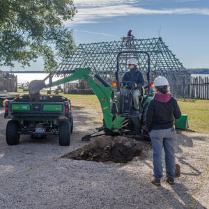 Senior Staff Archaeologist Anna Shackelford uses a backhoe to begin the excavations just outside the Church Tower as Staff Archaeologist Ren Willis looks on.