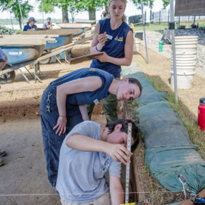 Field School student Lexy Marcuson measures the depth of the excavation walls with help from Archaeological Intern Katherine Griffith and Staff Archaeologist Natalie Reid.