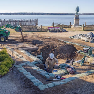 Archaeological Field Technician Josh Barber finishes up the excavations west of the Church Tower as Staff Archaeologist Ren Willis uses a front end loader to backfill a completed section.