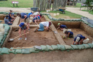 Field school students and staff work together excavating and cleaning test units.