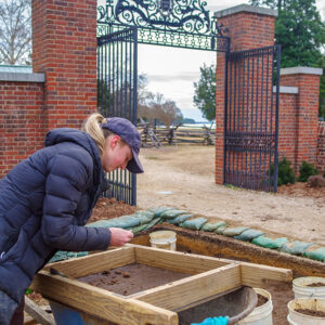 Archaeological Field Technician Katie Griffith screens for artifacts near the Colonial Dames of America gate.