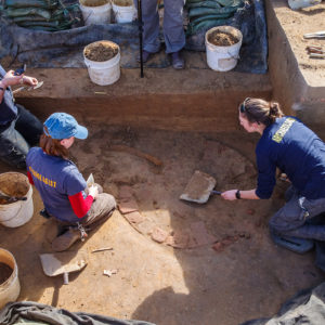 Archaeologists Hannah Barch, Natalie Reid, and Anna Shackelford excavate the soil over the well to expose the well ring bricks.
