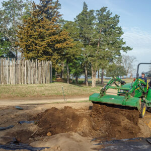 Staff Archaeologist Natalie Reid uses a front loader to backfill the cellar excavations.