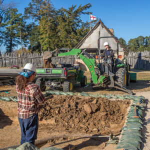 To speed up the dig, Staff Archaeologist Ren Willis uses a backhoe to remove backfill from previous excavations just west of the Church Tower.