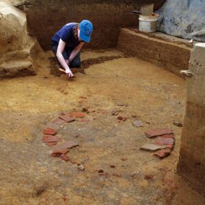 Staff Archaeologist Natalie Reid slowly scraping away soil in the well excavations.