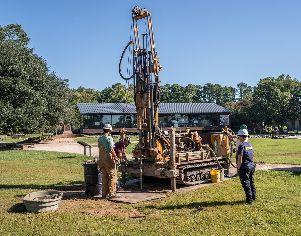 Staff Archaeologist Caitlin Delmas supervises the boring process near the Dale House. The Archaearium museum is at rear.