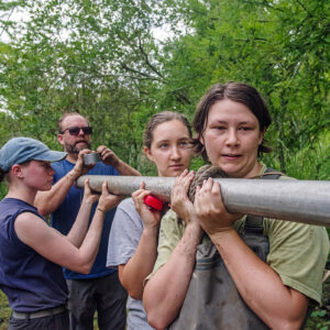 TerraSearch Geophysical's Dr. David Leslie caps off the aluminum tube holding a vibracore soil sample from the Pitch and Tar Swamp. Staff Archaeologist Natalie Reid and field school students Julia Womersley-Jackman and Lexy Marcuson hold the tube.