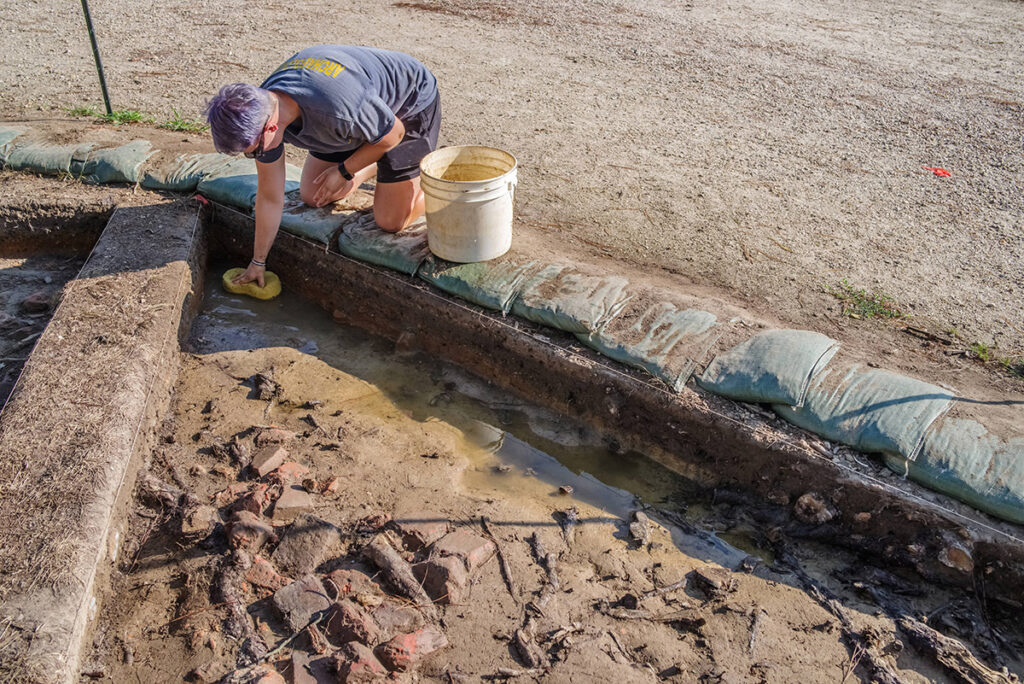 Staff Archaeologist Caitlin Delmas soaks up rainwater prior to continuing excavations of a 19th-century brick rubble feature north of Fort Pocahontas.