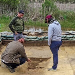 Archaeologists Sean Romo, Gabriel Brown, and Mary Anna Hartley discuss the excavations of the zig-zag ditch near the clay borrow pit.