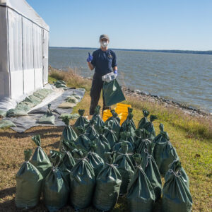 Archaeological Field Technician Katie Griffith stands behind a number of soil samples taken from the 1607 Burial Ground. These will be processed by the flotation machine to help search for artifacts.