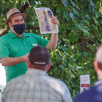 a tour guide wearing a face mask holds up a photo for his audience