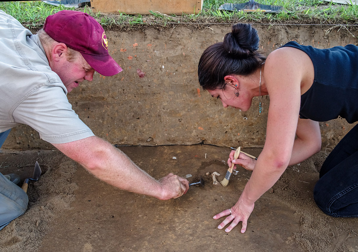 Senior Staff Archaeologist Sean Romo and Assistant Curator Emma Derry excavate animal bones found near the burial ground inside James Fort.