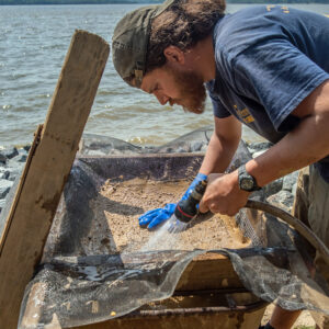 Archaeological Field Technician Josh Barber uses window screen to look for tiny objects that would fall through other screens.