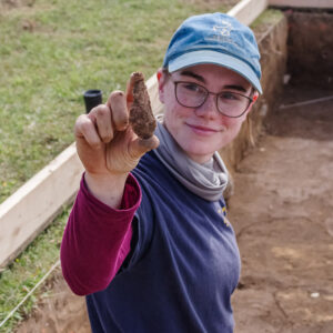 Staff Archaeologist Natalie Reid holds a projectile point found during the burial excavations.